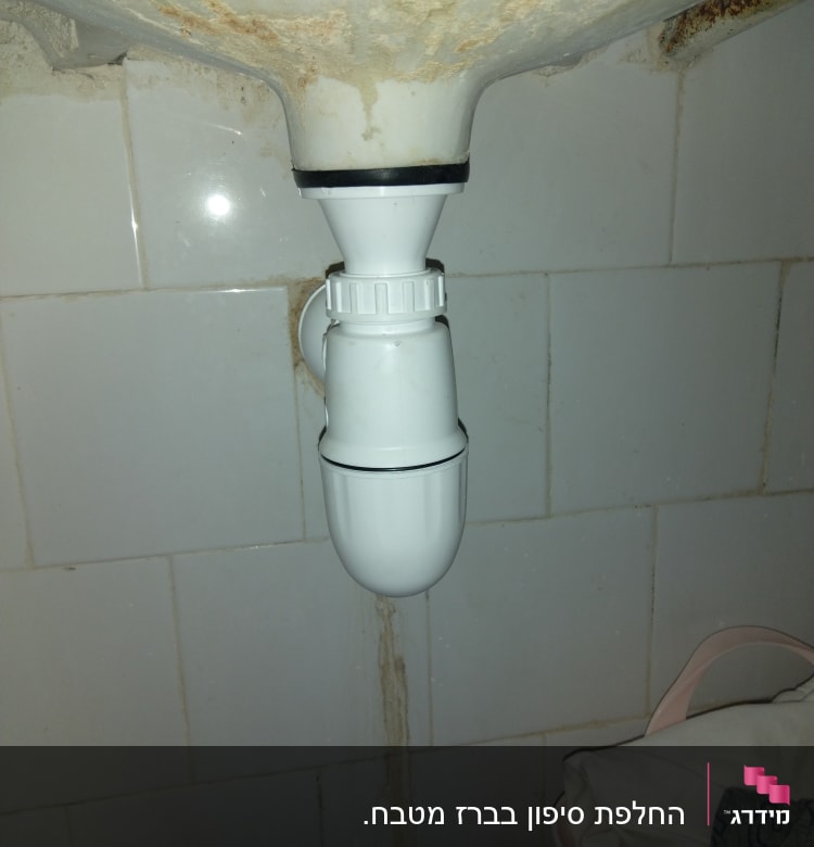 צינור ניקוז לבן מתחת לכיור עם חיבורי פלסטיק